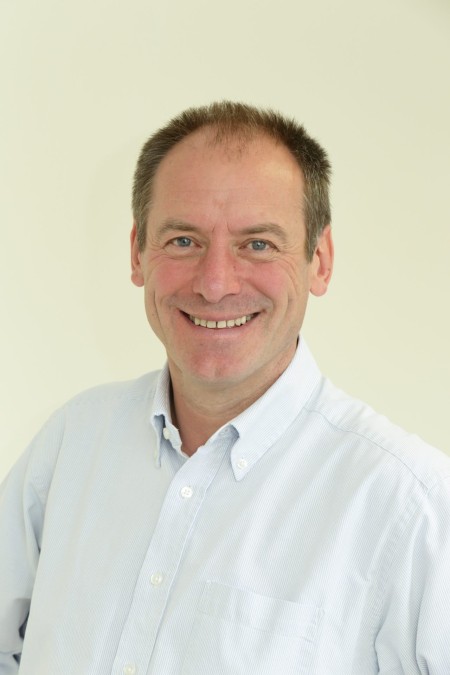 A man with short brown hair, smiling.