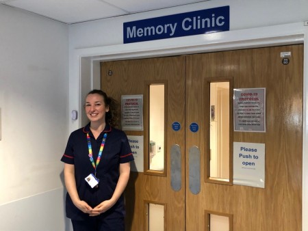 A photograph of a woman stood outside of the memory clinic.